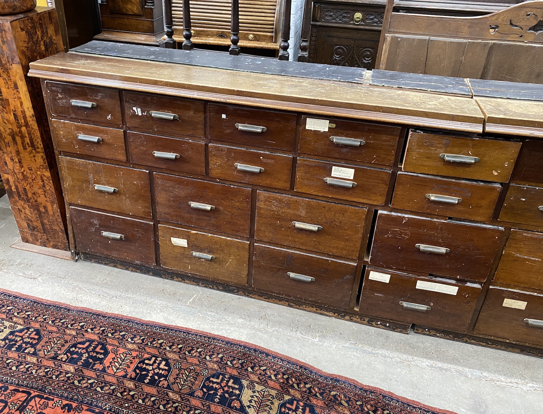 An apothecary bank of twenty eight drawers, now in two sections, length 260cm, depth 41cm, height 91cm